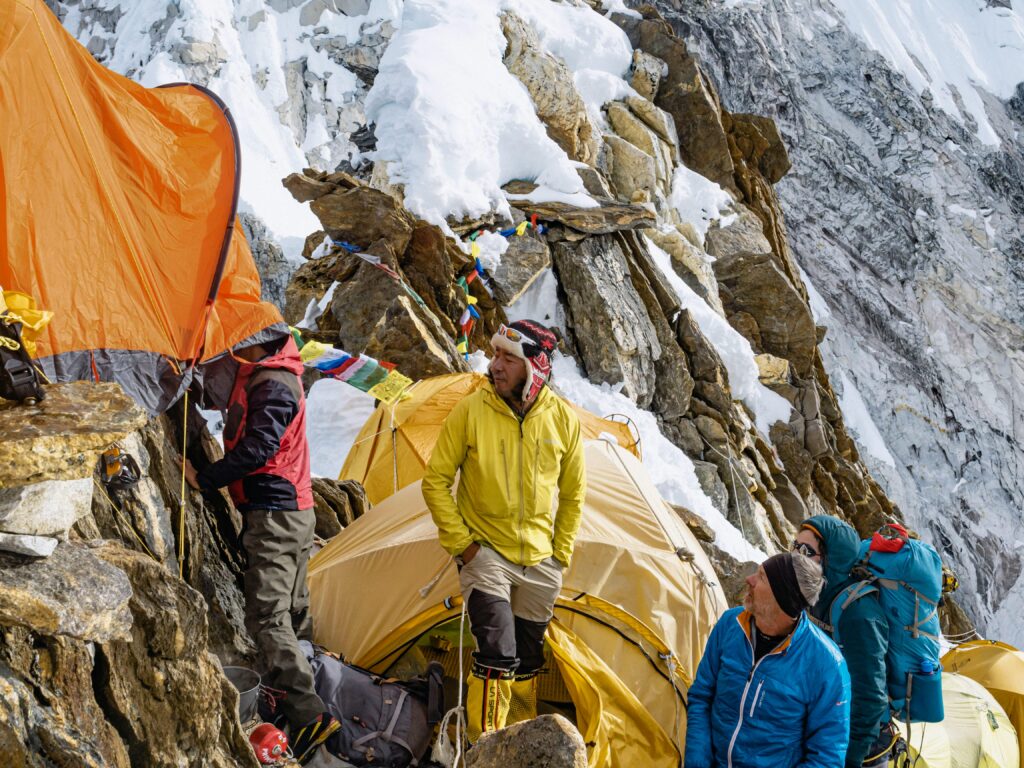 Expedition group setting up tents on a Himalayan mountain, capturing the adventure of high-altitude trekking.