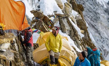 Expedition group setting up tents on a Himalayan mountain, capturing the adventure of high-altitude trekking.