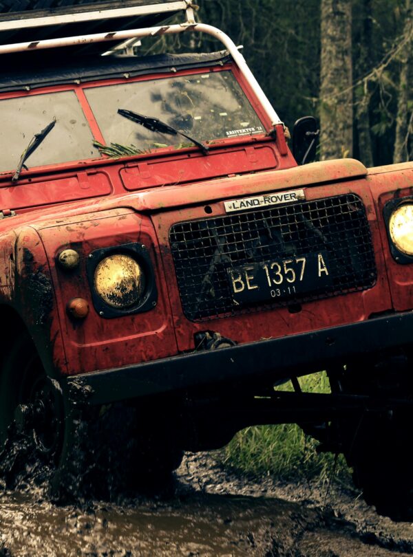 A rugged vintage Land Rover conquers a muddy trail, showcasing off-road capabilities and adventure spirit.