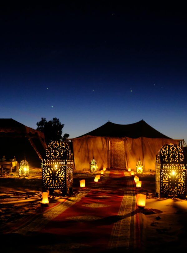 Illuminated tents with lanterns at twilight in Egypt's desert, creating a magical ambiance.
