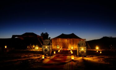 Illuminated tents with lanterns at twilight in Egypt's desert, creating a magical ambiance.