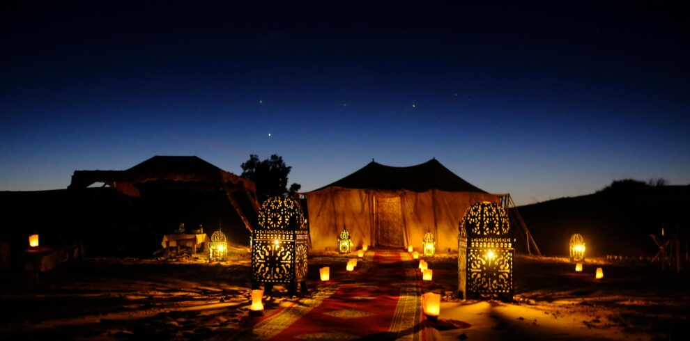 Illuminated tents with lanterns at twilight in Egypt's desert, creating a magical ambiance.