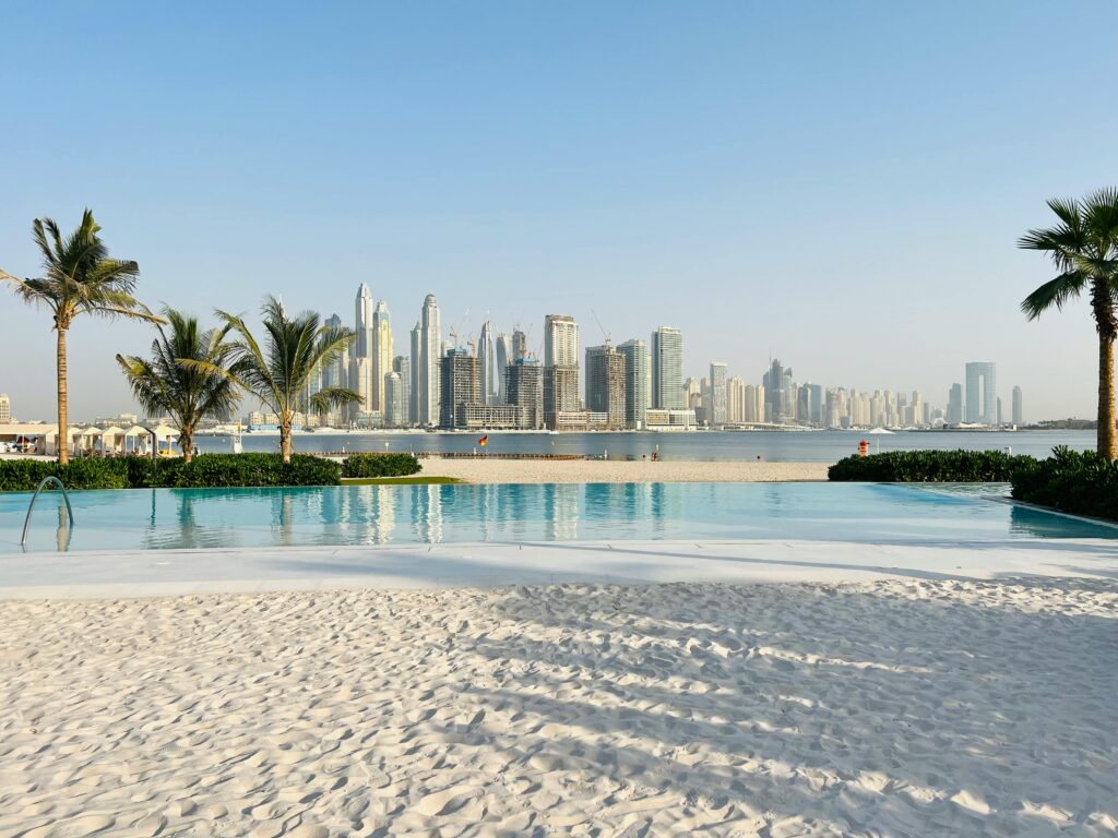 Luxurious beachfront pool overlooking the iconic Dubai skyline on a sunny day.