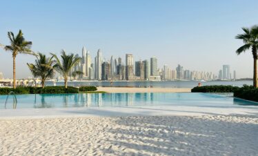 Luxurious beachfront pool overlooking the iconic Dubai skyline on a sunny day.