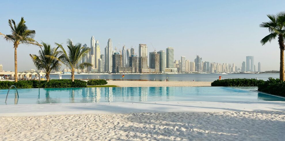 Luxurious beachfront pool overlooking the iconic Dubai skyline on a sunny day.