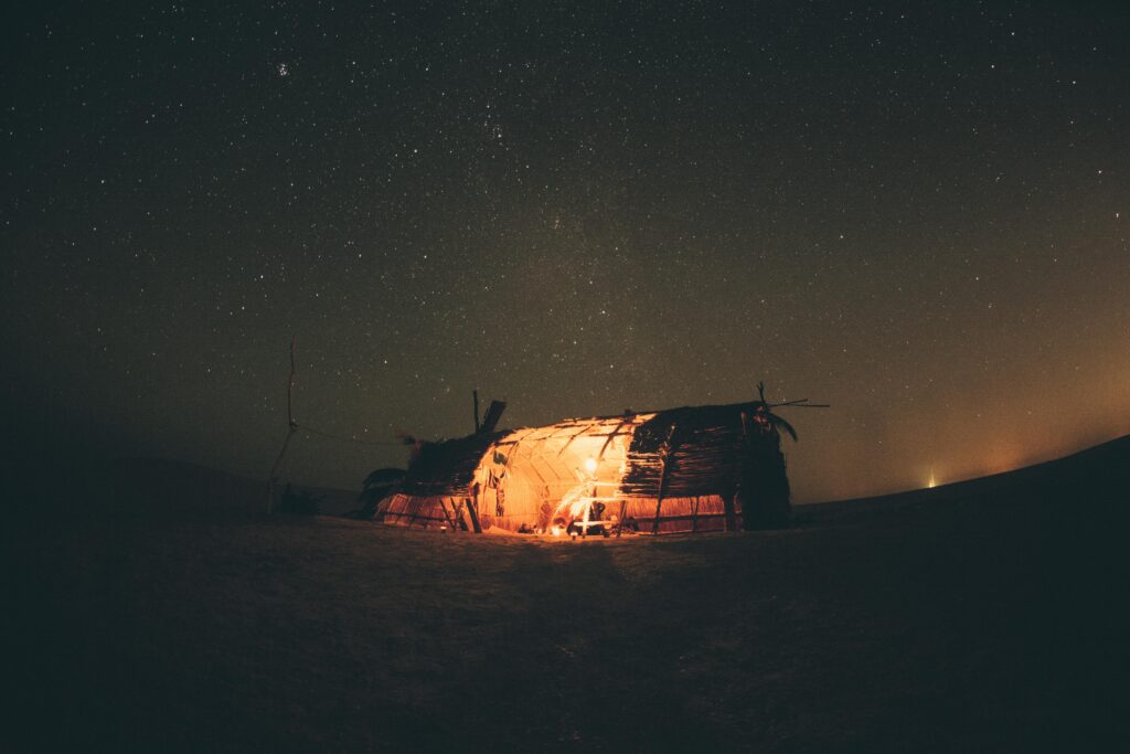 A serene night in Egypt's desert, capturing a starry sky and a warmly lit tent under the Milky Way.