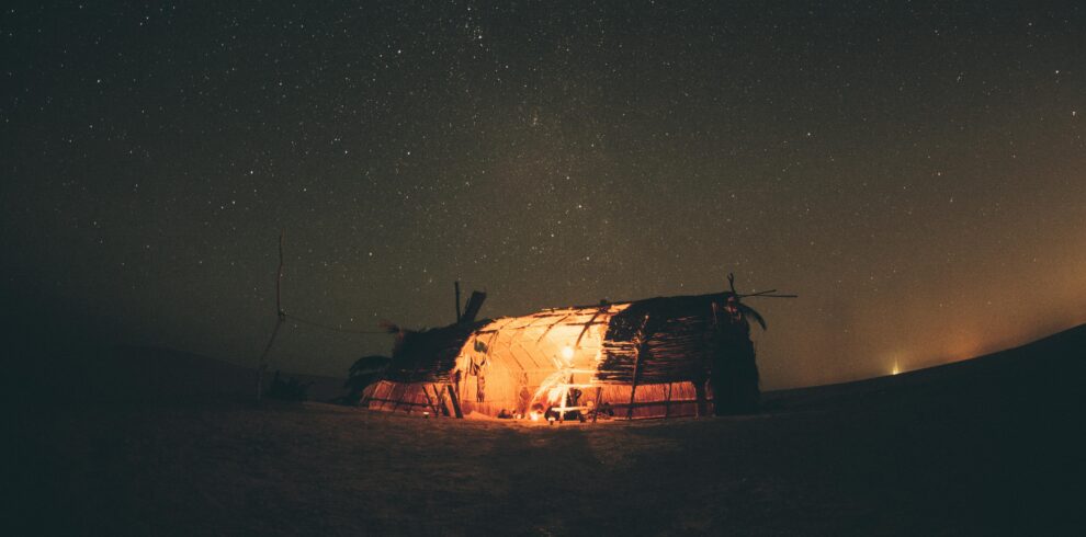 A serene night in Egypt's desert, capturing a starry sky and a warmly lit tent under the Milky Way.