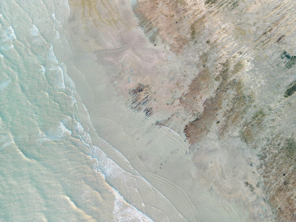 Aerial view capturing the tranquil meeting of ocean waves and sand on a serene beach.