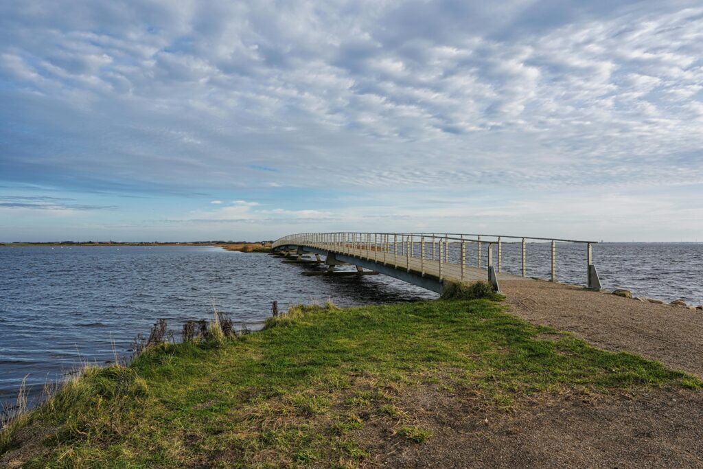 Idyllic bridge over coastal waters in Søndervig, Denmark, capturing a serene, natural landscape.