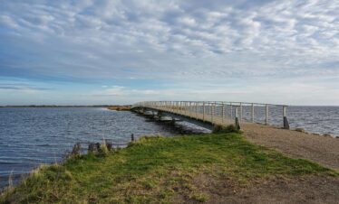 Idyllic bridge over coastal waters in Søndervig, Denmark, capturing a serene, natural landscape.
