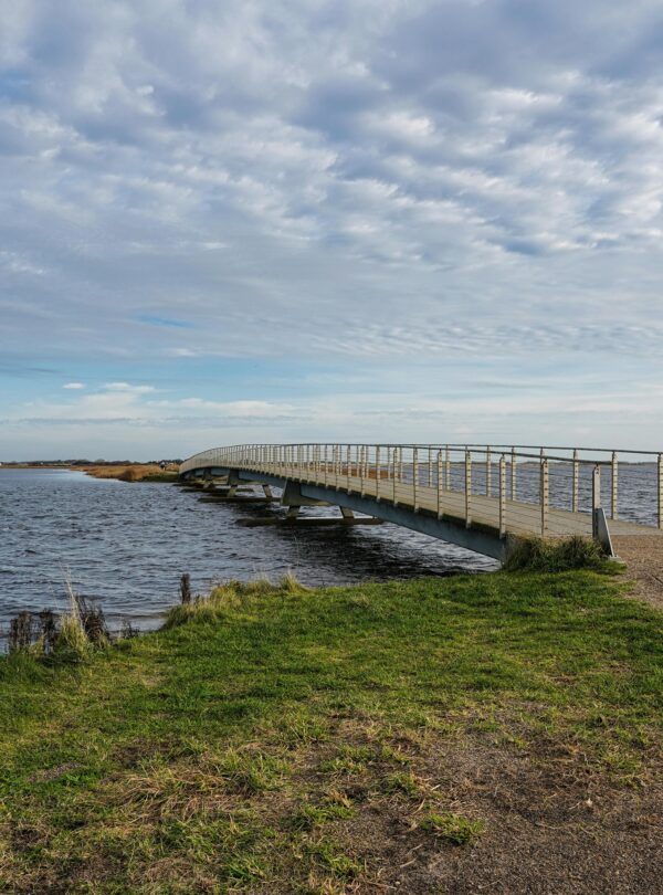Idyllic bridge over coastal waters in Søndervig, Denmark, capturing a serene, natural landscape.